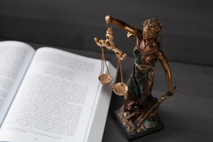 Foto gerechtigkeitsstatue und buch auf grauer oberfläche