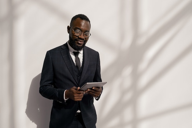 Foto gerente africano joven feliz en traje de desplazamiento en tableta