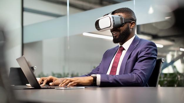 Gerente afroamericano sonriente usando gafas vr y computadora portátil