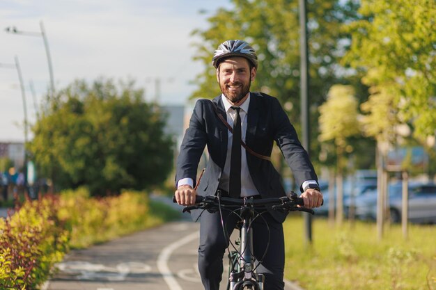 Foto gerente alegre con casco que viaja al trabajo en la mañana soleada