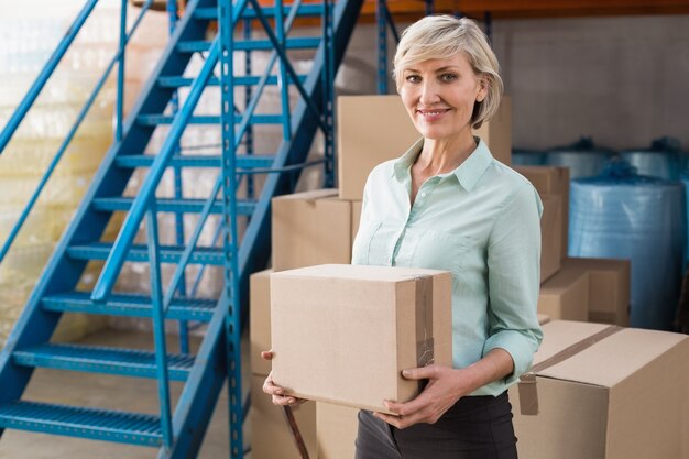 Gerente de almacén sonriente con caja de cartón