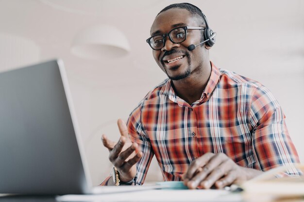 Gerente amigable del servicio de atención al cliente Hombre afroamericano en auriculares recibe llamadas