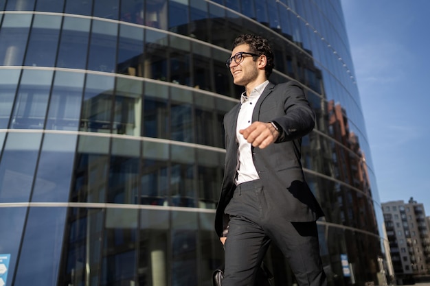 El gerente con anteojos es un hombre positivo que va a trabajar en la oficina con un traje de negocios.