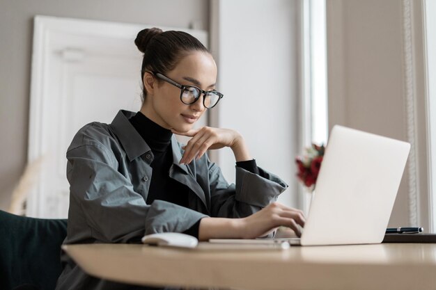 El gerente con anteojos trabaja en línea en el lugar de trabajo de Internet Una mujer usa una computadora