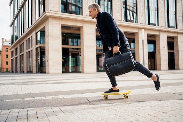 El gerente se apresura a asistir a una reunión con un traje de negocios. Un empresario monta una patineta.