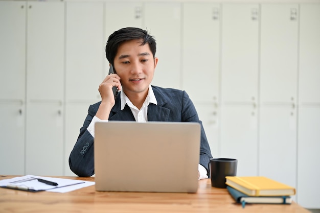 Un gerente asiático profesional está hablando por teléfono con su cliente de negocios