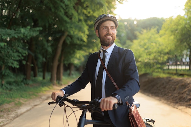 Foto gerente bonito andando de bicicleta para o local de trabalho em dia ensolarado