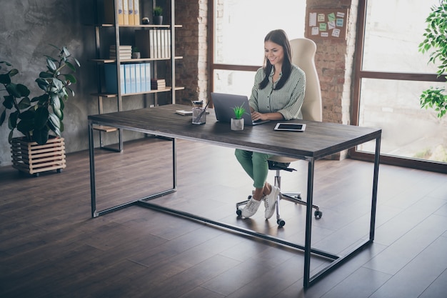 Gerente chica sentarse escritorio en la oficina loft trabajando en equipo portátil