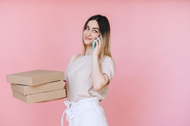 Gerente com um telefone nas mãos e caixas de pizza em um fundo rosa