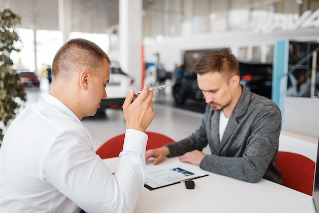 Gerente y comprador hacen la compra de auto nuevo en showroom.