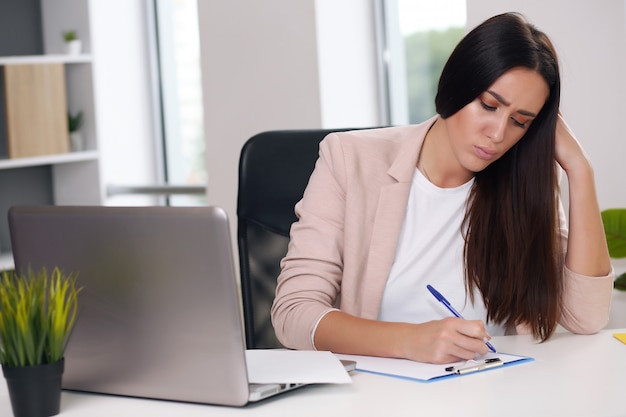 Gerente de contenido femenino joven hace notas con un lápiz