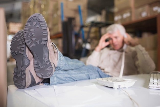 Gerente de armazém usando telefone na mesa