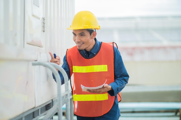 Gerente de canteiro de obras asiático em pé usando colete de segurança e capacete pensando no canteiro de obras Retrato de trabalhador manual ou arquiteto indonésio com satisfação