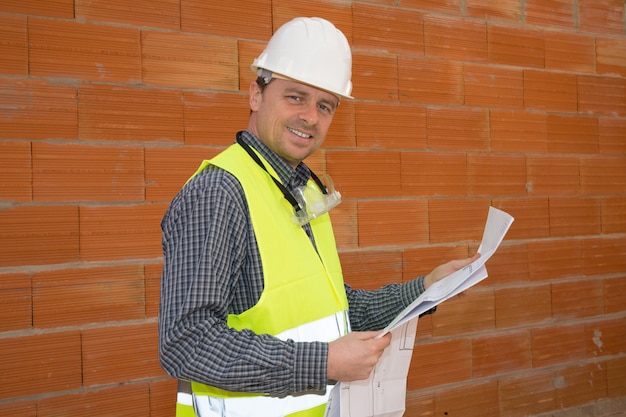 Gerente de construção sorridente em pé no estaleiro