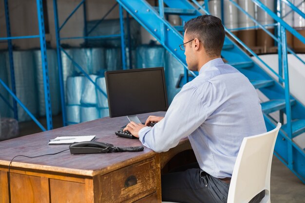 Gerente de depósito que trabalha no computador