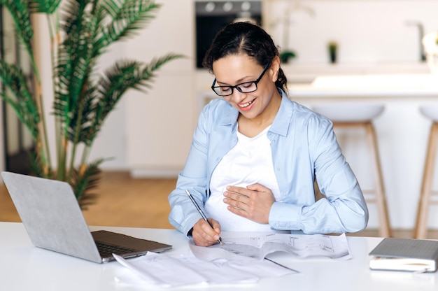 Gerente de designer de óculos de raça mista de mulher grávida sorrindo