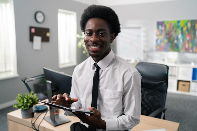 Gerente de empresa bonito empresário americano africano com afro senta-se em sua mesa vestido de terno