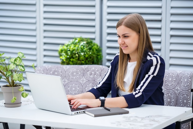 Gerente de empresário jovem bem-sucedido, sentado à mesa com um laptop e um bloco de notas, trabalhando em um novo projeto de desenvolvimento, a aluna escreve um relatório no computador