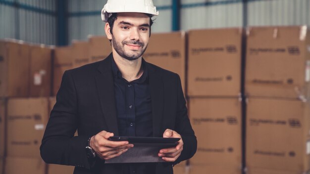 Gerente de fábrica usando um tablet em um depósito ou fábrica