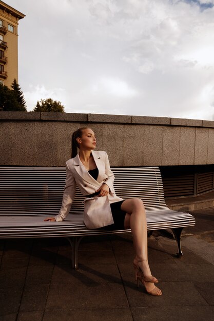 Foto gerente de garota com roupas da cidade elegante se senta em um banco.