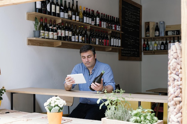 Gerente de loja de vinhos verificando os dados de vinho usando negócios on-line de tablet