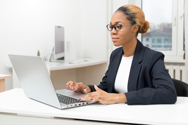 Gerente de mulher de negócios americano africano trabalhando em um laptop.