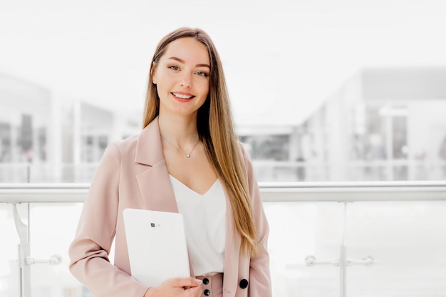 Foto gerente de mulher de negócios segurando tablet digital em pé no centro de negócios