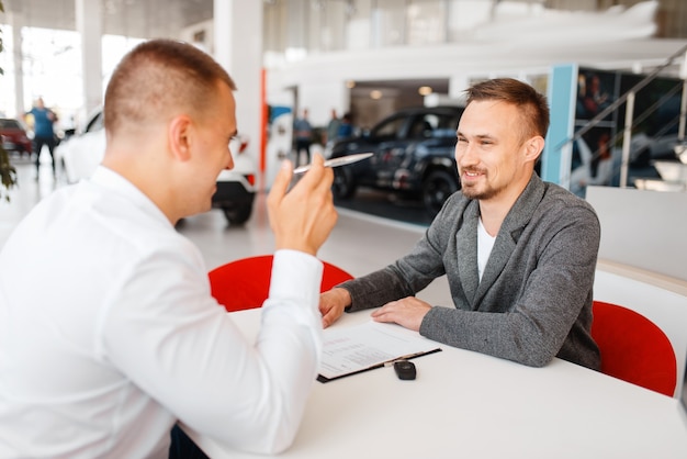 Gerente e comprador fazem a compra do carro novo em showroom.