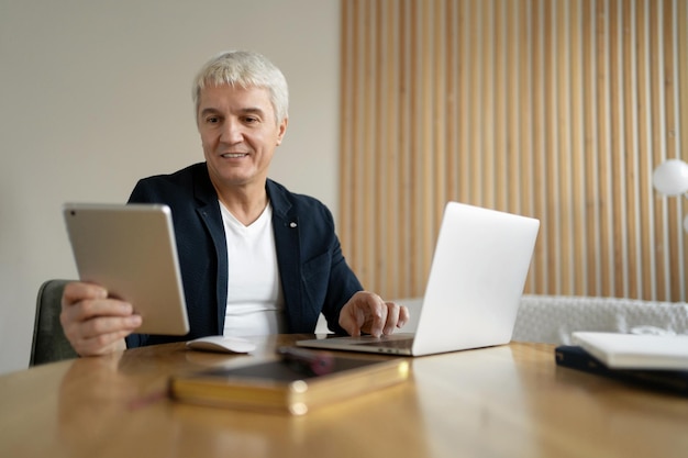 El gerente de edad trabaja en la oficina Lugar de trabajo en coworking Hombre en línea navega por internet