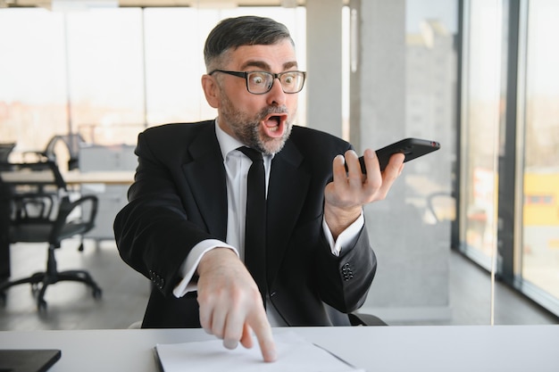 Foto gerente ejecutivo experimentado peleando con un empleado en el móvil gritando y gritando sobre mal informe y fracaso con el proyecto jefe enojado enojado por errores de software en la aplicación para el trabajo