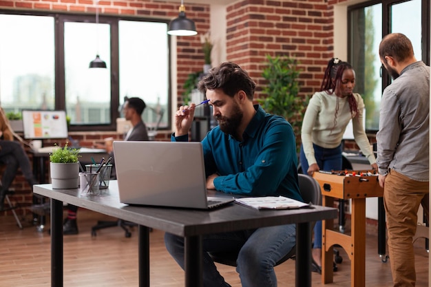 Gerente ejecutivo pensativo que tiene dudas sobre el proyecto de marketing analizando la facturación de la empresa en la computadora. Empresario trabajando en colaboración empresarial en la oficina de inicio. equipo diverso