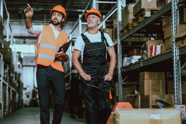 Foto gerente em hardhat falando com o trabalhador do armazém