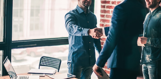 El gerente de la empresa da la bienvenida al cliente con un apretón de manos