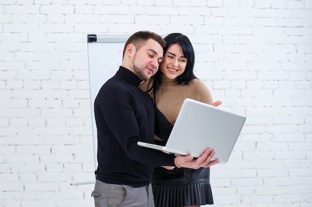 Gerente de empresario y mujer sonriente están de pie con el portátil y mirando la pantalla. Párese sobre un fondo blanco.