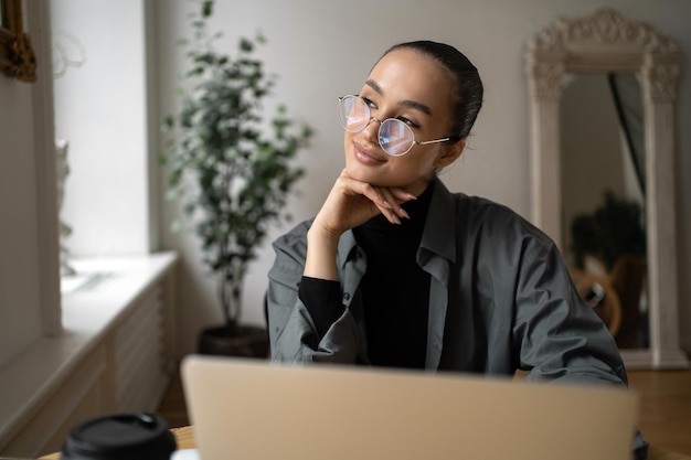 La gerente es una mujer con anteojos que trabaja en la oficina usando una computadora portátil en línea