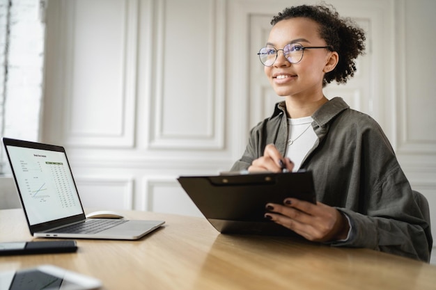 El gerente es una mujer que usa una computadora portátil que trabaja en la oficina Informe financiero de la empresa espacial de coworking