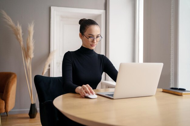El gerente es un trabajo rutinario diario de una mujer joven que usa un lugar de trabajo de computadora portátil