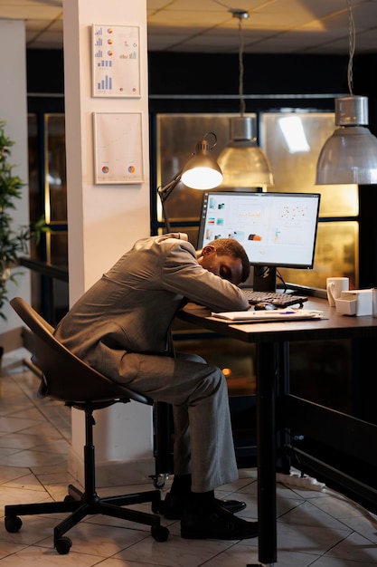 Gerente exausto e sobrecarregado de trabalho dormindo em uma mesa de escritório no escritório de uma startup depois de planejar o plano de investimento da empresa tarde da noite Empreendedor workaholic trabalhando em um projeto de marketing