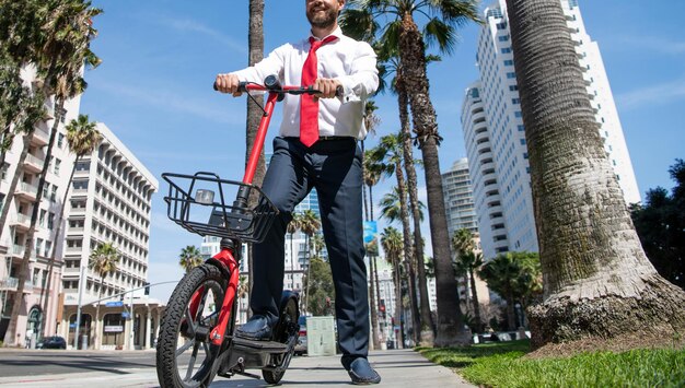 Gerente feliz em roupas formais usa escooter no estilo de vida urbano de rua