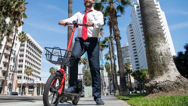 Gerente feliz en ropa formal usa scooter en el estilo de vida urbano de la calle