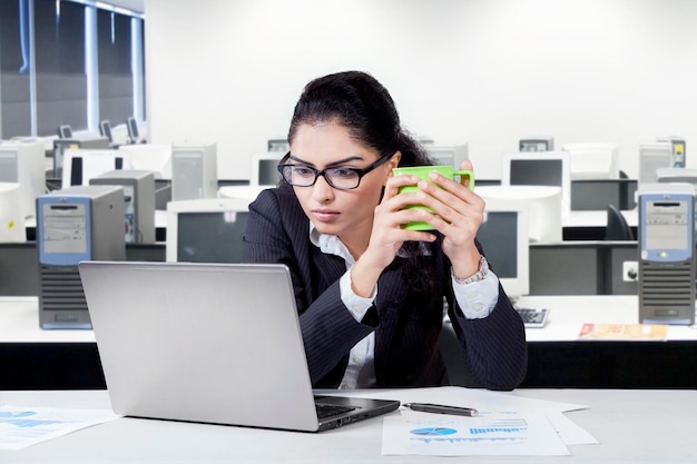 Foto gerente femenina con una computadora portátil sosteniendo café
