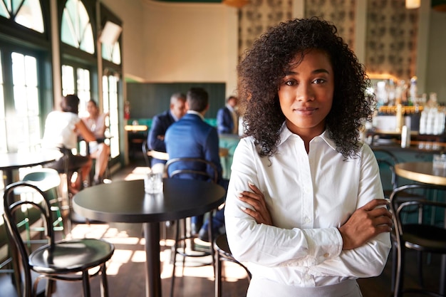 Gerente feminina de um bar de coquetéis ocupado num restaurante com clientes na câmara.