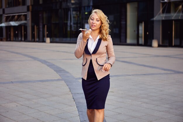 Foto gerente feminina em um terno de negócios fala ao telefone usando o viva-voz