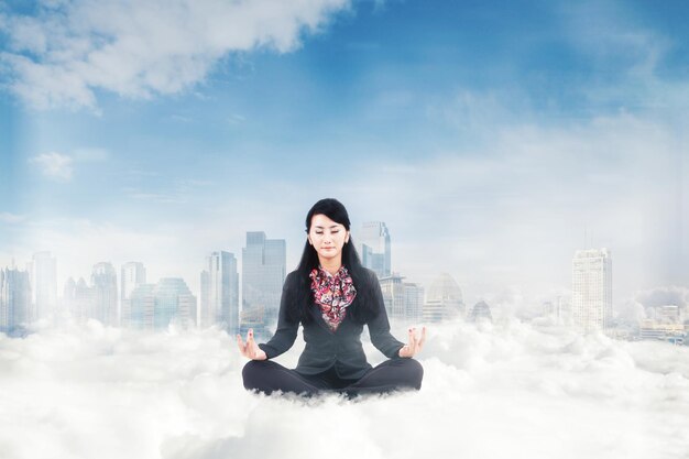 Gerente feminina meditando acima das nuvens