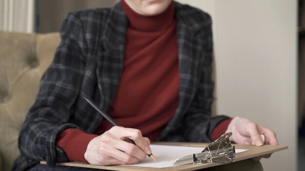 Gerente feminino mãos na cadeira fazendo anotações em papel segurando um lápis