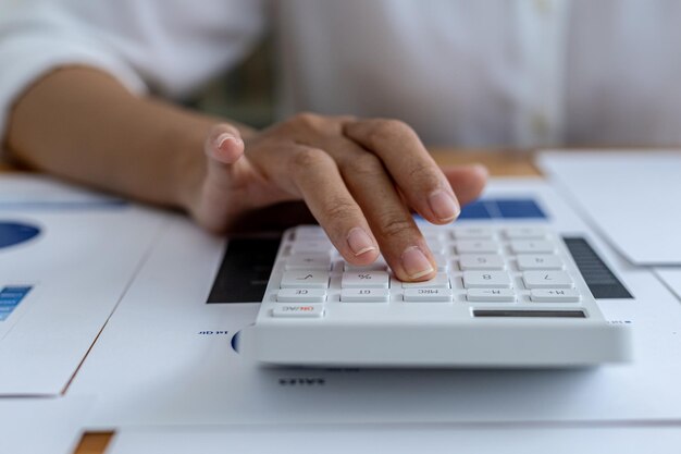 El gerente de finanzas de la empresa está usando una calculadora, usa una calculadora para calcular los números en los documentos financieros de la empresa que los empleados del departamento crean como documentos de reunión.