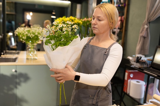 Gerente de floristería empacando un ramo y preparándolo para la entrega