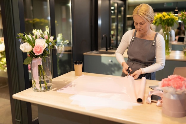 Gerente de floristería envolviendo flores en papel de regalo