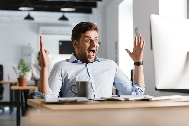 Foto gerente homem feliz e surpreso se alegra ao usar o computador