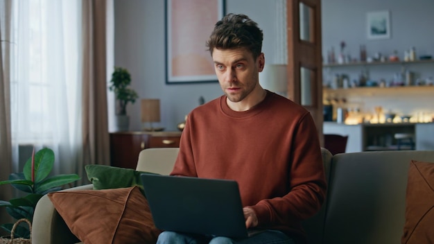 Gerente en línea serio trabajando en la casa de la computadora portátil de cerca inteligente freelancer mecanografía